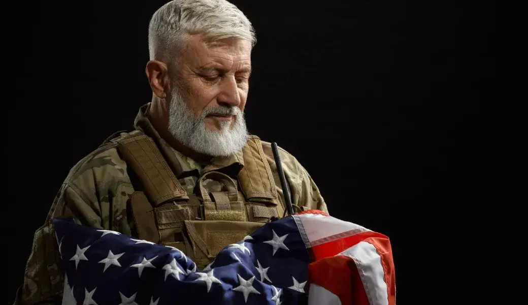 Veteran respectfully holding folded American flag, symbolizing honor and service.